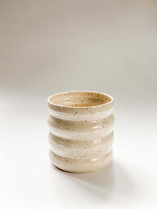 Wheel thrown planter with 4 defined bumps in a cream and brown speckled clay