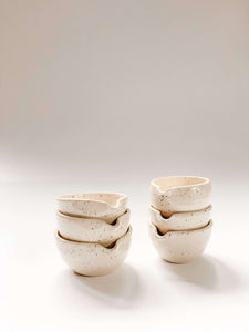 Two stacks of three small wheel thrown bowl with a pouring spout in cream clay with speckles