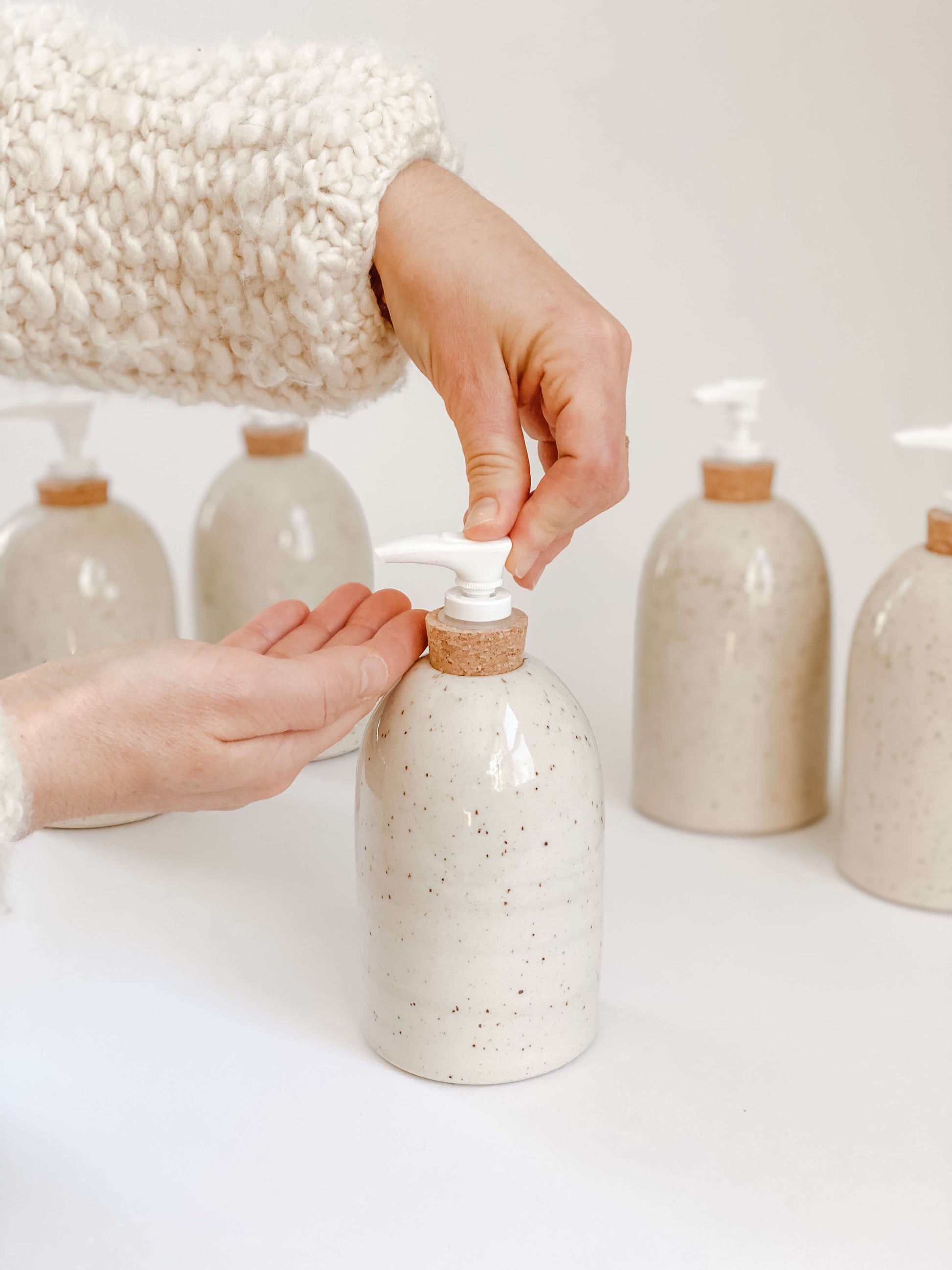 Woman's hand showing how to use speckled stoneware pottery soap pump 