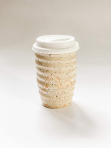 Wheel thrown travel mug in cream and brown speckled clay with hand painted curving line design 