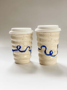 Two wheel thrown travel mugs in cream and brown speckled clay with hand painted blue curving line design 