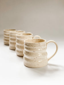 4 wheel thrown mugs with pronounced spiral throwing marks in cream and brown speckled clay  