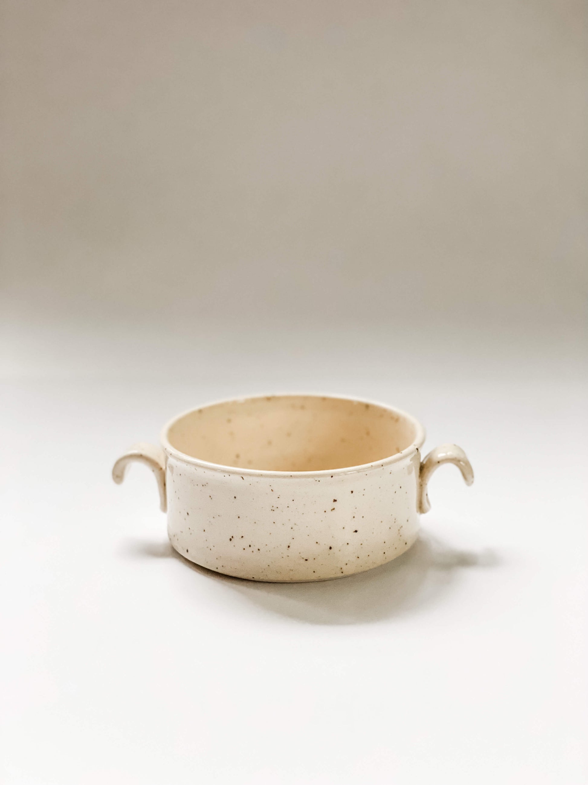 Wheel thrown cylindrical soup bowls with two hooked handles in a cream and brown speckled clay